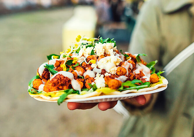 Close-up of healthy vegetarian vegan street food at a street food festival. Pita bread with salad, avocado, cauliflower and chickpeas.