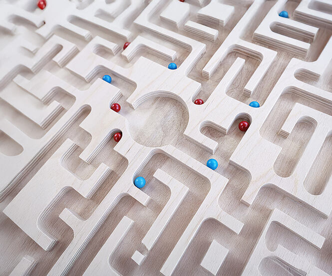 Blue and red balls searching for solutions to the center of a wooden maze